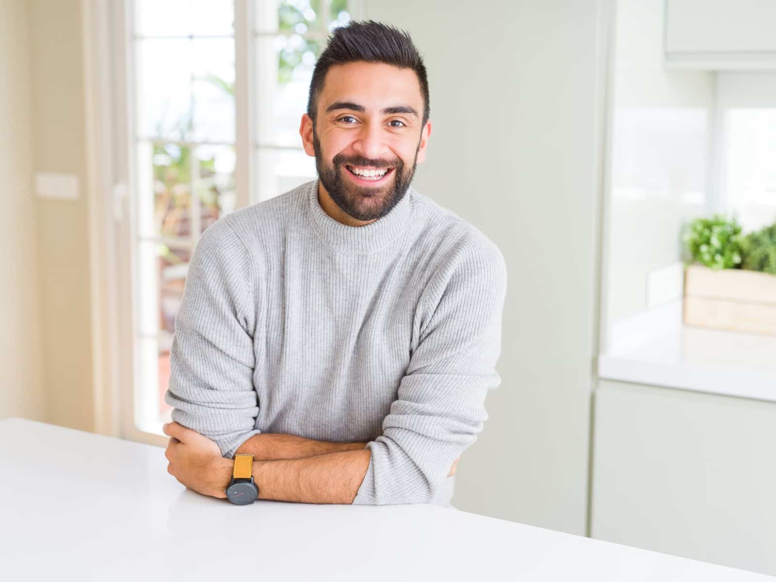 Man smiling in kitchen after receiving gum disease treatment